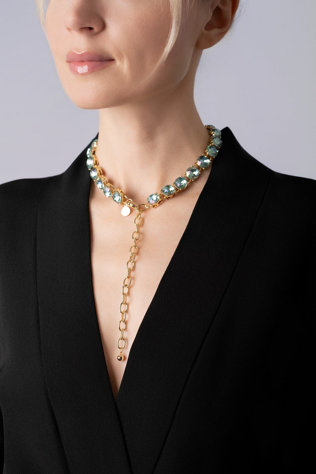 Woman wearing a blue crystals necklace with a black kimono on a light blue background.