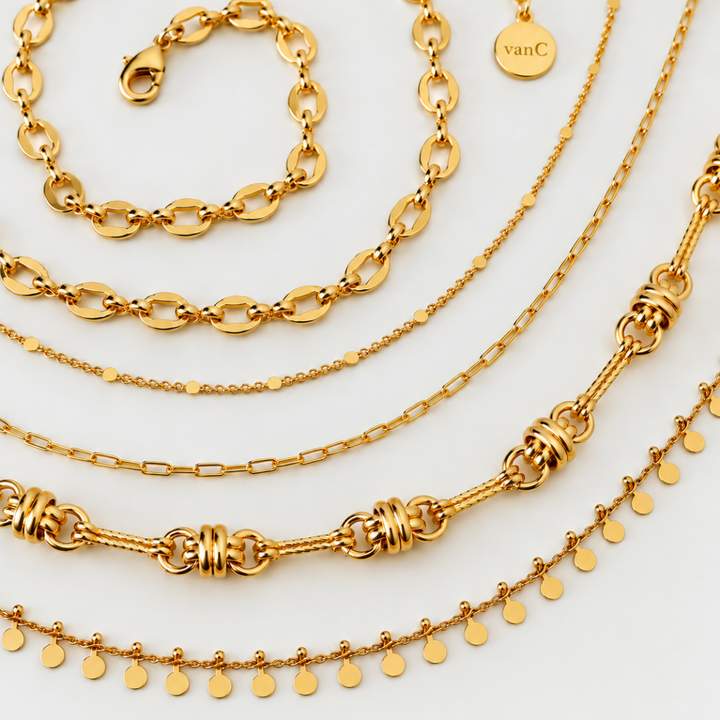 Close up of different gold plated chains from Blauw van C jewellery brand, arranged on a clean white background. A small round brand tag is visible with the brand logo ‘van C'.