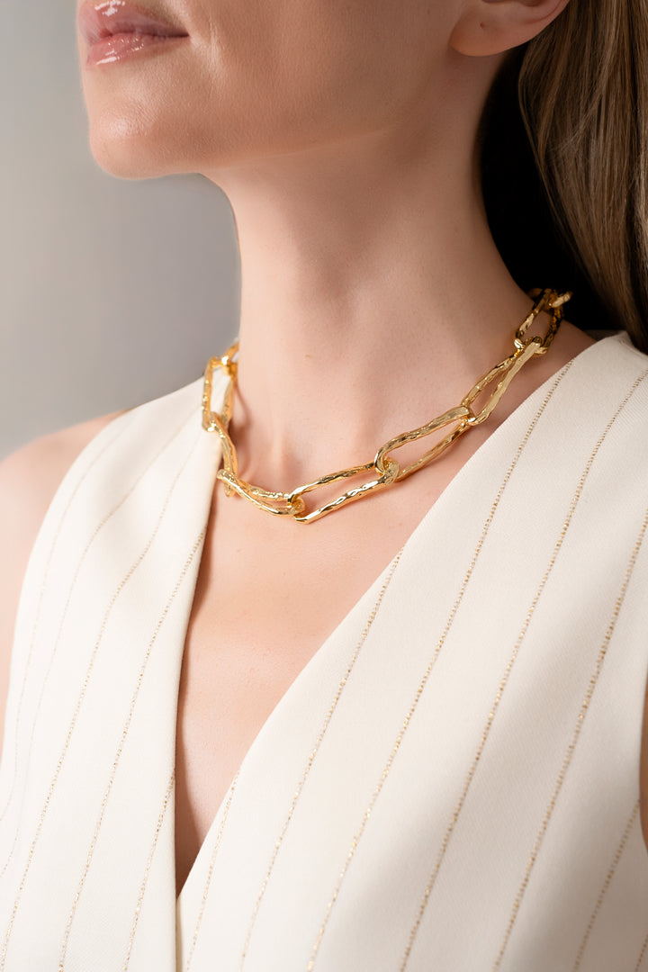 Gold Connecting Worlds Necklace worn by a woman with a cream vest