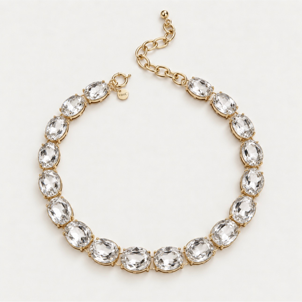 Blauw van C Glow Oversize Crystal Necklace with oval white crystals in 18-karat gold-plated settings, laid flat on a neutral background, showing the clasp, brand tag and extension chain.