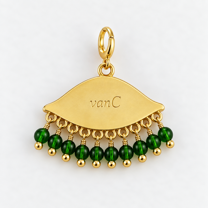 Gold plated eye-shaped pendant charm with dangling green faceted beads engraved with 'vanC' logo, shown on a clean white background.