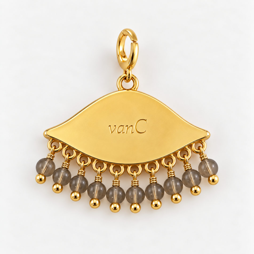 Gold plated See the world  eye-shaped charm pendant with dangling sand translucent beads, shown on a clean white background. The brand logo 'vanC' is engraved on the charm.