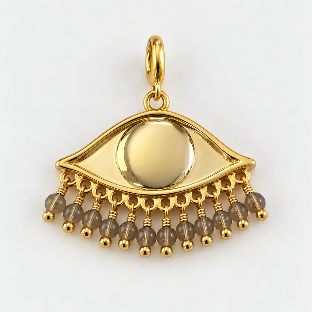 Gold plated See the world eye-shaped pendant with dangling sand toned beads, photographed on a clean neutral background.