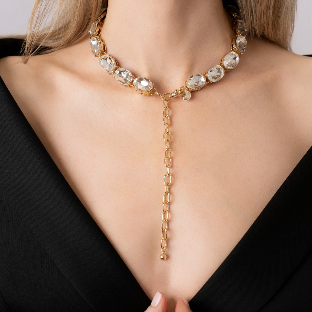 Gold-plated necklace with white crystals with front drop chain on a model wearing a black top.