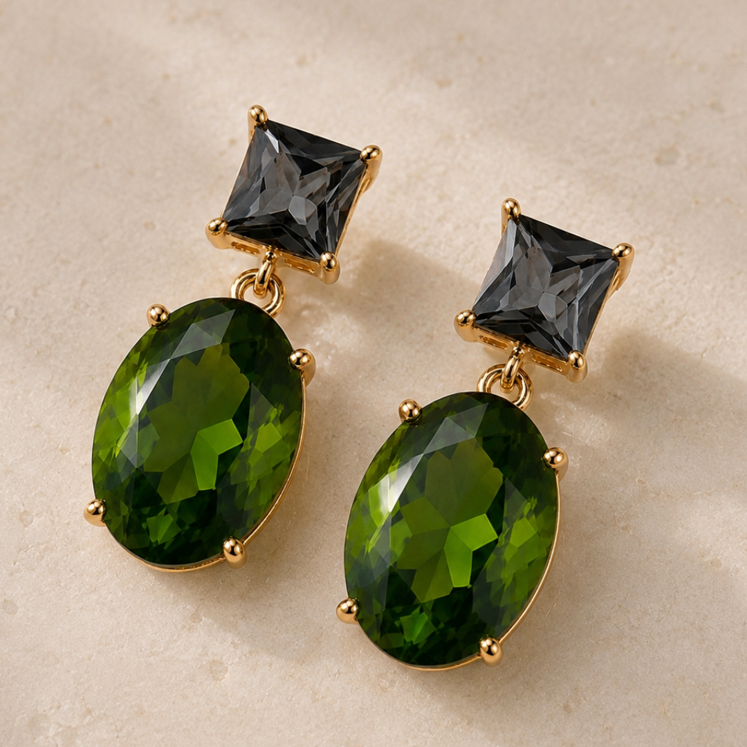 Two Way Glow green and smokey grey crystal drop earrings in 18K gold plating on a neutral stone background.