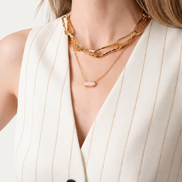 Blauw van C Andalus Necklace in light pink, layered with Connecting Worlds chunky gold chain on a model wearing a cream pinstriped waistcoat.