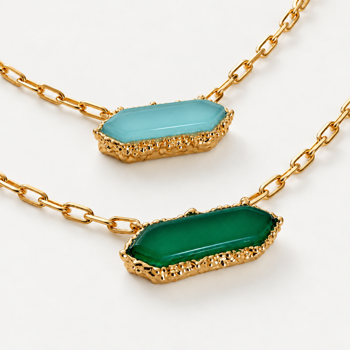 Close-up of Blauw van C Andalus necklaces in Cadiz Blue and Granada Green, showing faceted agate pendants and decorative gold-plated settings.